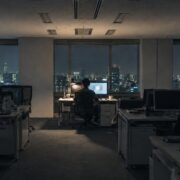 照明の落ちた深夜のオフィスで一席だけ灯るデスク